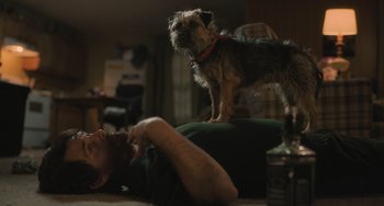 Movie still from “Strays” (2023), directed by Josh Greenbaum – A man laying on the ground with a dog; Medium shot, Low angle
