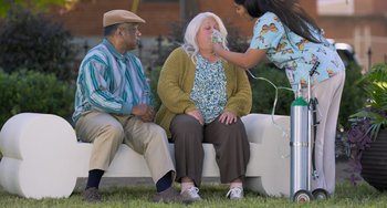Movie still from “Strays” (2023), directed by Josh Greenbaum – A woman is putting makeup on a woman's face; Wide shot, Over the shoulder angle