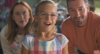 Movie still from “Strays” (2023), directed by Josh Greenbaum – A little girl wearing glasses and a checkered shirt; Close Up shot, Over the shoulder angle