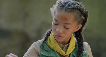 Movie still from “Strays” (2023), directed by Josh Greenbaum – A young girl with braids and a yellow neck scarf; Close Up shot, High angle