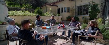 Movie still from “Studio 666” (2022), directed by BJ McDonnell – A group of people sitting around a table; Wide shot, High angle