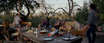 Movie still from “Studio 666” (2022), directed by BJ McDonnell – A group of people sitting at a picnic table; Wide shot, High angle