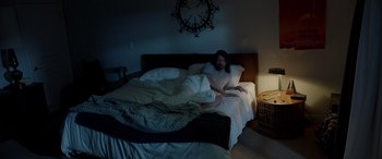 Movie still from “Studio 666” (2022), directed by BJ McDonnell – A man laying on a bed in the dark; Wide shot, High angle