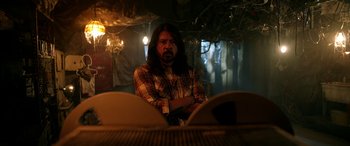 Movie still from “Studio 666” (2022), directed by BJ McDonnell – A man with long hair sitting in a dark room; Medium shot, Low angle