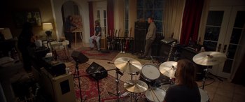 Movie still from “Studio 666” (2022), directed by BJ McDonnell – Two men are sitting in a living room with their musical instruments; Wide shot, High angle