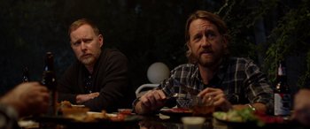 Movie still from “Studio 666” (2022), directed by BJ McDonnell – A couple of men sitting at a table with food; Medium shot, Over the shoulder angle