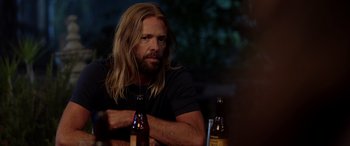 Movie still from “Studio 666” (2022), directed by BJ McDonnell – A man sitting at a table with two beer bottles; Close Up shot, Over the shoulder angle