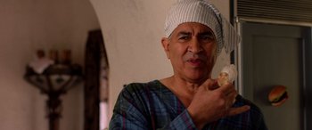 Movie still from “Studio 666” (2022), directed by BJ McDonnell – An older man wearing a white hat and a blue plaid shirt; Close Up shot, Over the shoulder angle