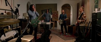 Movie still from “Studio 666” (2022), directed by BJ McDonnell – A group of people playing guitar in a room; Wide shot, Low angle