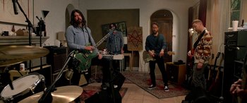 Movie still from “Studio 666” (2022), directed by BJ McDonnell – A group of people playing instruments in a room; Wide shot, Low angle