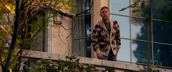 Movie still from “Studio 666” (2022), directed by BJ McDonnell – A man standing on a ledge looking out of a window; Medium shot, Low angle