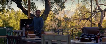 Movie still from “Studio 666” (2022), directed by BJ McDonnell – A man standing in front of an outdoor table; Wide shot, Over the shoulder angle