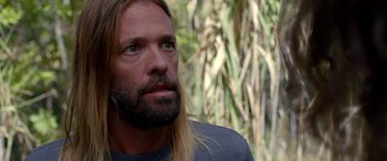 Movie still from “Studio 666” (2022), directed by BJ McDonnell – A person with long hair and a beard; Close Up shot, Over the shoulder angle