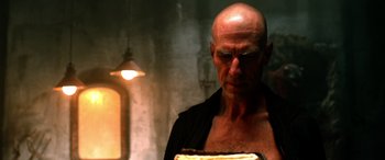 Movie still from “Studio 666” (2022), directed by BJ McDonnell – A bald man is looking down at a piece of cake; Close Up shot, Low angle