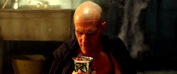 Movie still from “Studio 666” (2022), directed by BJ McDonnell – A bald man holding a silver cup in his hands; Close Up shot, Low angle