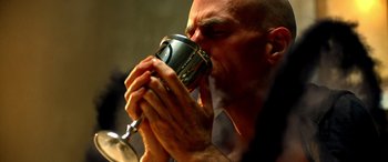 Movie still from “Studio 666” (2022), directed by BJ McDonnell – A bald man drinking from a metal cup; Extreme Close Up shot, Low angle
