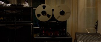 Movie still from “Studio 666” (2022), directed by BJ McDonnell – An analog stereo tape recorder with two reels of tape; Extreme Close Up shot, Low angle