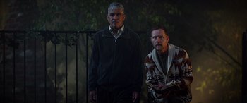 Movie still from “Studio 666” (2022), directed by BJ McDonnell – Two men standing next to each other in front of a fence; Medium shot, Low angle