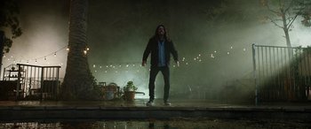 Movie still from “Studio 666” (2022), directed by BJ McDonnell – A man with a long hair and a beard standing in the rain; Wide shot, Low angle