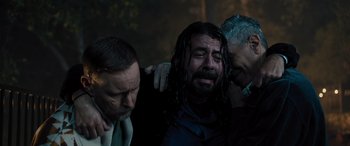 Movie still from “Studio 666” (2022), directed by BJ McDonnell – A group of men standing next to each other in the dark; Medium shot, High angle