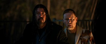 Movie still from “Studio 666” (2022), directed by BJ McDonnell – Two men standing next to each other in the dark; Medium shot, Over the shoulder angle