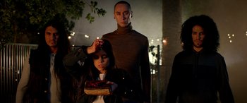 Movie still from “Studio 666” (2022), directed by BJ McDonnell – A man standing next to a woman holding a piece of food; Medium shot, Low angle