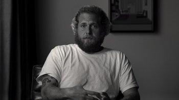 Movie still from “Stutz” (2022), directed by Jonah Hill – A man with long hair and a beard sitting in a chair; Close Up shot, Low angle