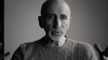 Movie still from “Stutz” (2022), directed by Jonah Hill – An older man wearing a gray sweater and looking at the camera; Close Up shot, Low angle