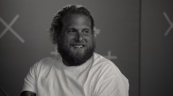 Movie still from “Stutz” (2022), directed by Jonah Hill – Black and white photograph of a bearded man smiling; Close Up shot, Low angle