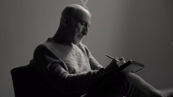 Movie still from “Stutz” (2022), directed by Jonah Hill – An older man writing on a piece of paper; Medium shot, Low angle