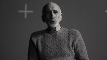 Movie still from “Stutz” (2022), directed by Jonah Hill – An older man wearing a sweater with a cross in the background; Close Up shot, Low angle