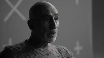 Movie still from “Stutz” (2022), directed by Jonah Hill – An older bald man wearing a sweater stares into the distance; Close Up shot, Over the shoulder angle