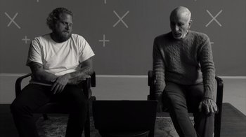 Movie still from “Stutz” (2022), directed by Jonah Hill – Two men sitting in a room next to each other; Medium shot, Over the shoulder angle