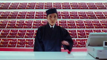 Movie still from “Charlie and the Chocolate Factory” (2005), directed by Tim Burton – A woman in a black hat is holding a red object in her hand; Medium shot, Low angle