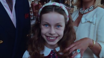 Movie still from “Charlie and the Chocolate Factory” (2005), directed by Tim Burton – A young girl with blue eyes smiling for the camera; Close Up shot, High angle