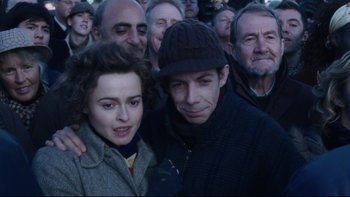 Movie still from “Charlie and the Chocolate Factory” (2005), directed by Tim Burton – A man and a woman standing next to each other in front of a crowd; Close Up shot, High angle