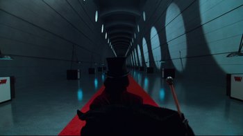 Movie still from “Charlie and the Chocolate Factory” (2005), directed by Tim Burton – A person in a top hat and a red carpet; Wide shot, Low angle