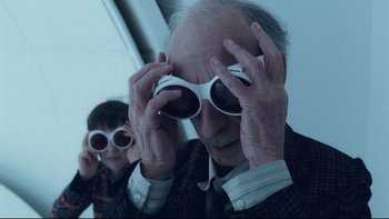 Movie still from “Charlie and the Chocolate Factory” (2005), directed by Tim Burton – An older man and a younger man looking at something through sunglasses; Close Up shot, Over the shoulder angle