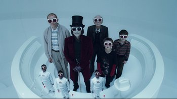 Movie still from “Charlie and the Chocolate Factory” (2005), directed by Tim Burton – A group of people standing next to each other; Medium shot, Low angle