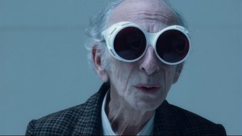 Movie still from “Charlie and the Chocolate Factory” (2005), directed by Tim Burton – An older man wearing sunglasses and a jacket; Close Up shot, Over the shoulder angle