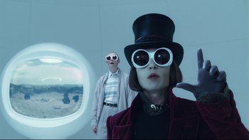 Movie still from “Charlie and the Chocolate Factory” (2005), directed by Tim Burton – A man and a woman wearing sunglasses and a hat; Medium shot, Over the shoulder angle