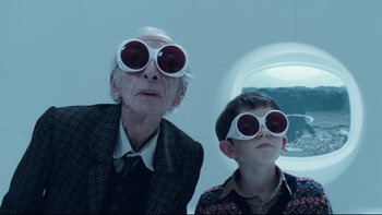 Movie still from “Charlie and the Chocolate Factory” (2005), directed by Tim Burton – A man and a boy wearing goggles and a suit; Medium shot, Low angle