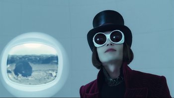 Movie still from “Charlie and the Chocolate Factory” (2005), directed by Tim Burton – A woman wearing a top hat and sunglasses; Close Up shot, Over the shoulder angle