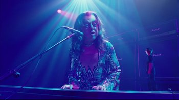 Movie still from “Charlie and the Chocolate Factory” (2005), directed by Tim Burton – A woman is playing the piano in front of a microphone; Medium shot, Low angle