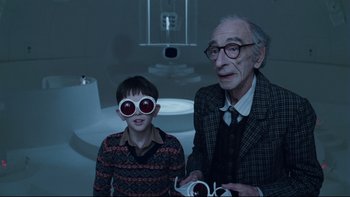 Movie still from “Charlie and the Chocolate Factory” (2005), directed by Tim Burton – An older man and a young boy wearing glasses; Medium shot, Over the shoulder angle