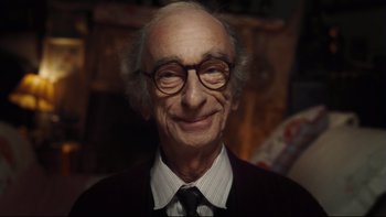 Movie still from “Charlie and the Chocolate Factory” (2005), directed by Tim Burton – An old man wearing glasses and a tie; Close Up shot, Over the shoulder angle