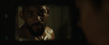 Movie still from “Suicide Squad” (2016), directed by David Ayer – A person looking at their reflection in a mirror; Extreme Close Up shot, Over the shoulder angle