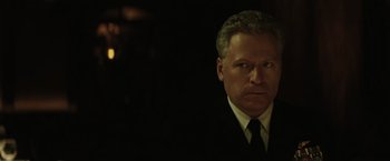 Movie still from “Suicide Squad” (2016), directed by David Ayer – A person wearing a suit and tie; Close Up shot, Over the shoulder angle