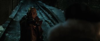 Movie still from “Suicide Squad” (2016), directed by David Ayer – A man holding a gun while standing next to a train; Close Up shot, Over the shoulder angle