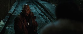 Movie still from “Suicide Squad” (2016), directed by David Ayer – A man with a cross on his neck standing in front of a car; Close Up shot, Over the shoulder angle